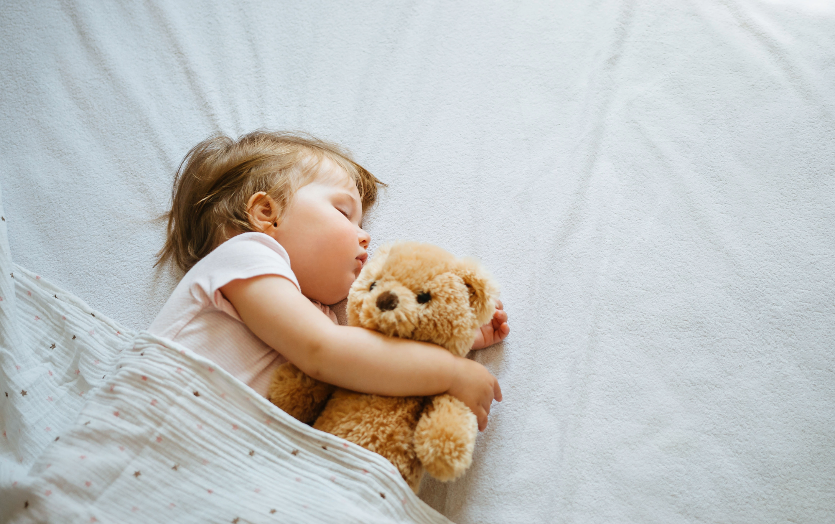 toddler sleeping with a teddy bear