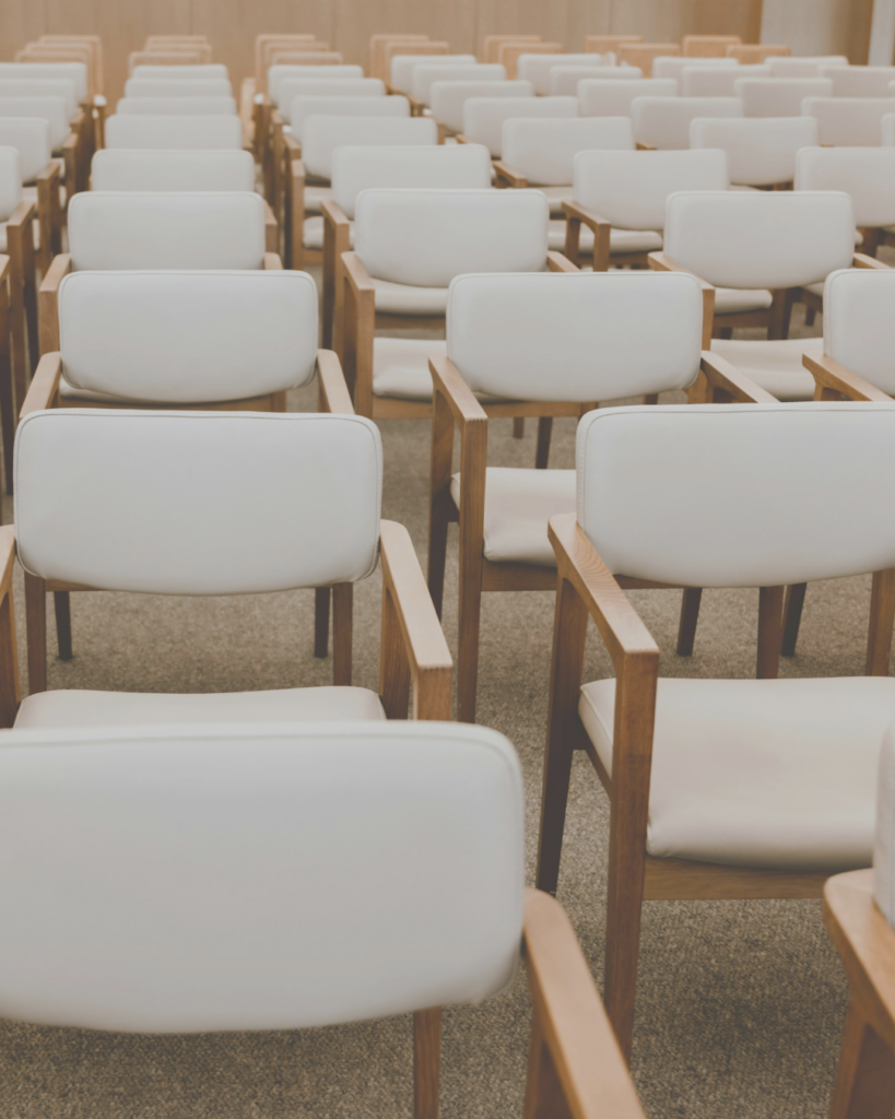 White and light wood chairs arranged in rows for speaking engagement.
